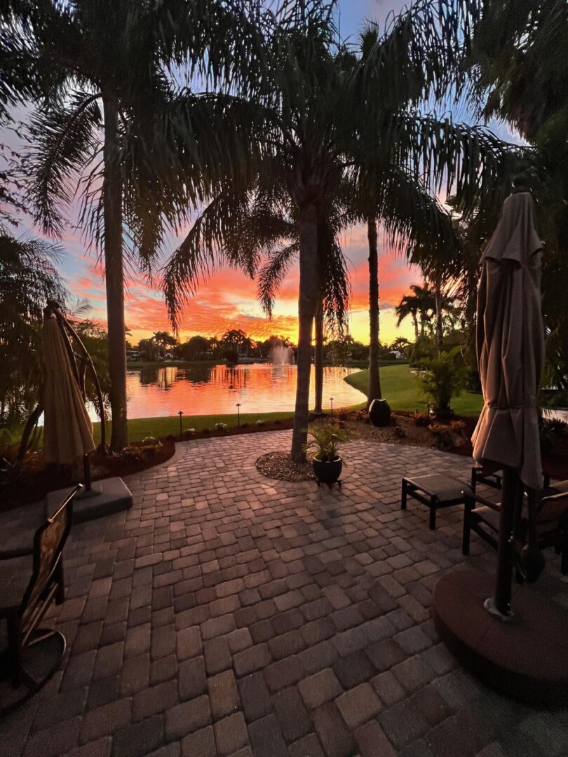 Sunset view over a tropical patio with palm trees and a lake. Sunset view over a tropical patio with palm trees and a lake.